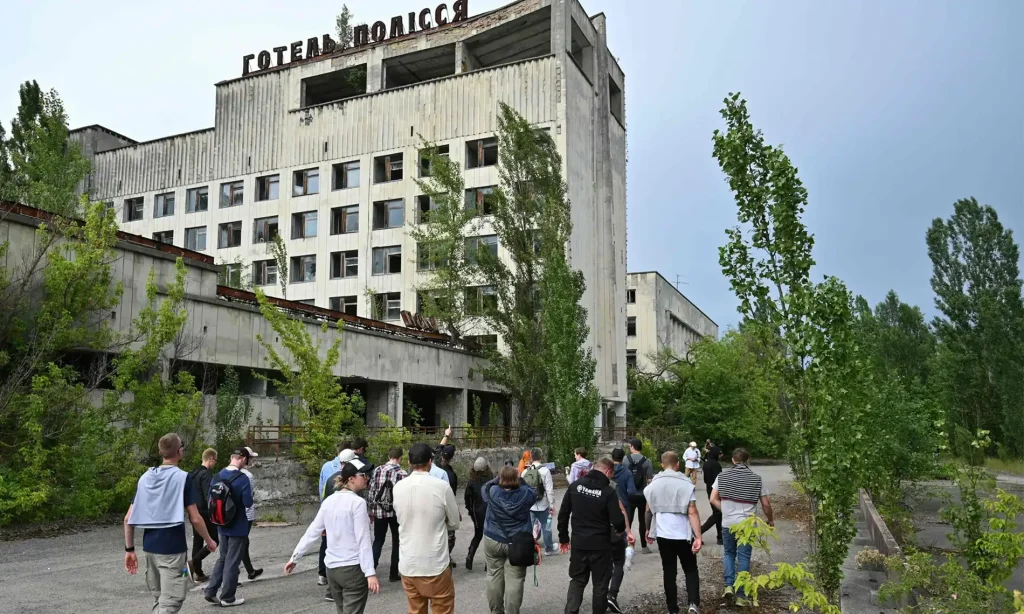 فاجعه چرنوبیل چگونه رخ داد؟ | مرگبارترین حادثه هستهای تاریخ 3 بازدیدکنندگان در جریان یک تور در منطقه ممنوعه چرنوبیل، در شهر متروکه پریپیات قدم میزنند.